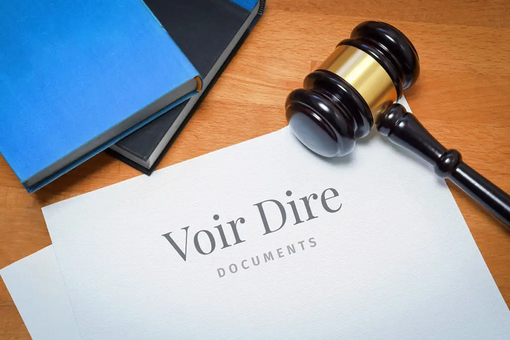 A gavel is on top of a paper with words reading 'Voir Dire Documents'. a blue book and black book is beside the gavel.