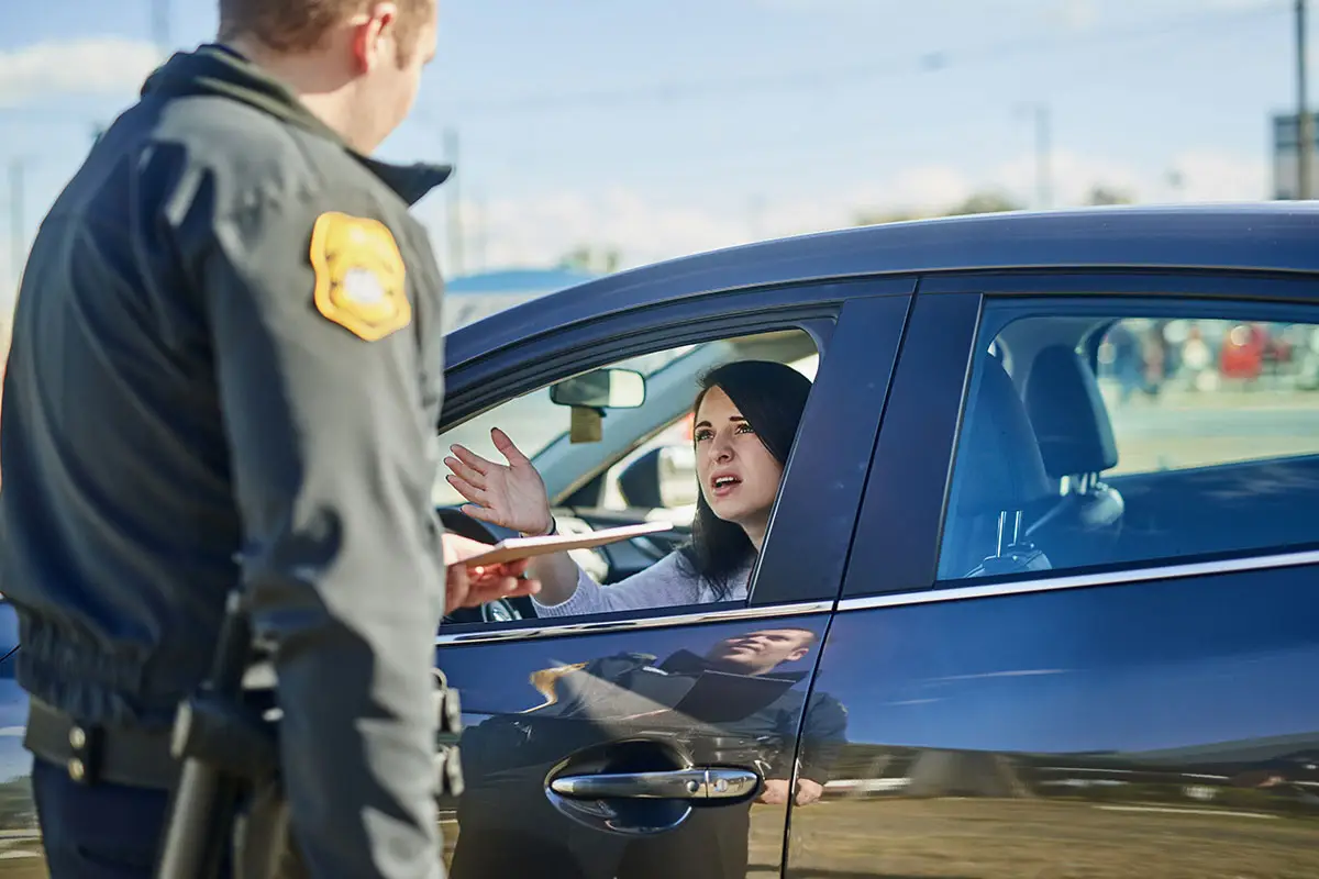 A woman resists to sign a ticket handed by a police officer.