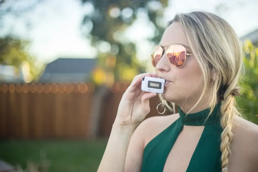 A woman takes a breathalyzer test using a BACtrac monitor.