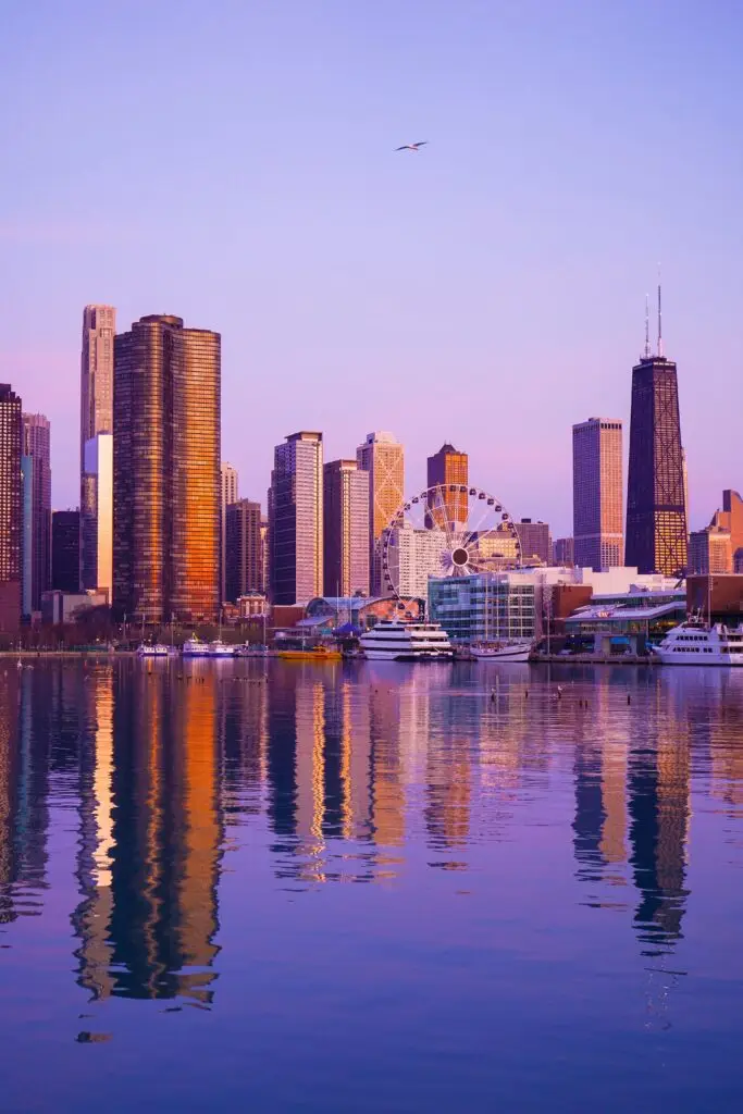 Skyscraper buildings with reflection in the water. The background shows the sun is about to set.