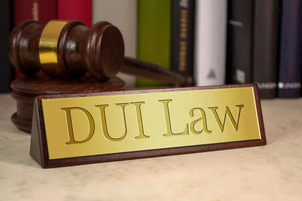 A desk plate with the words 'DUI Law'. A wooden gavel with sound block and books are on the background.