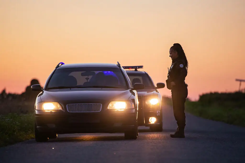 A police officer pulls over a car and is asking the driver questions.