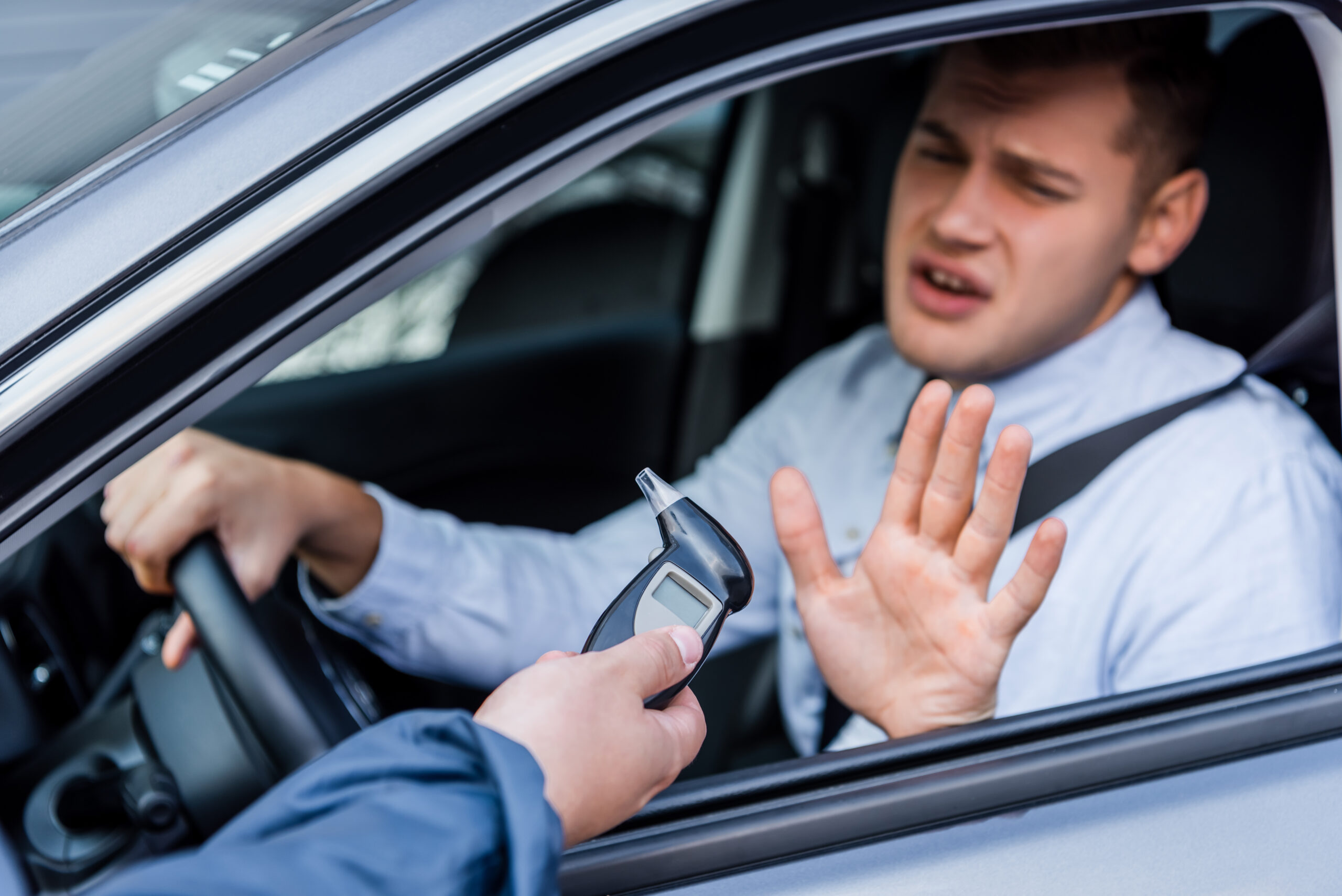 policeman giving breathalyzer to drunk driver showing refuse gesture.