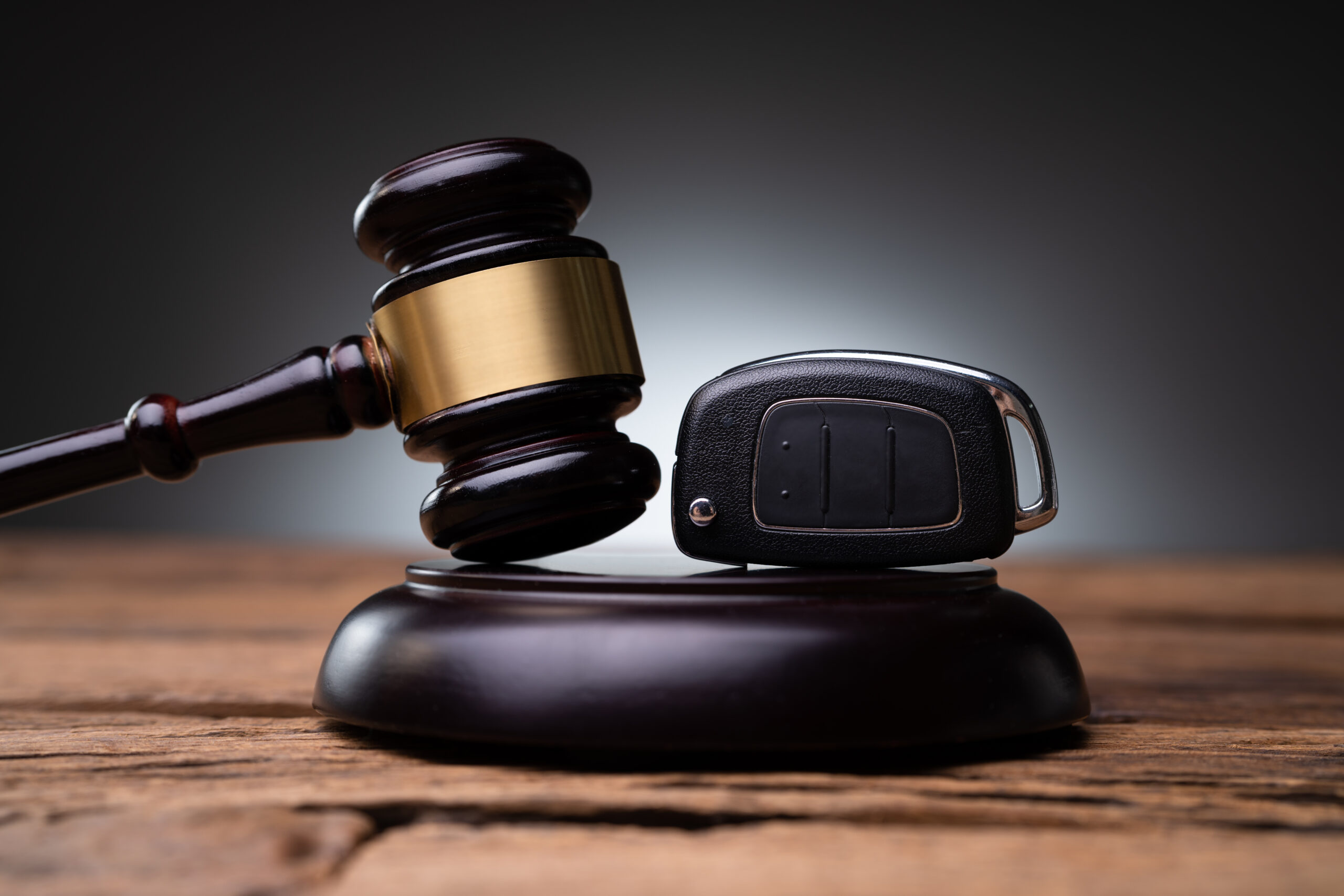 Car key and gavel on wooden table.